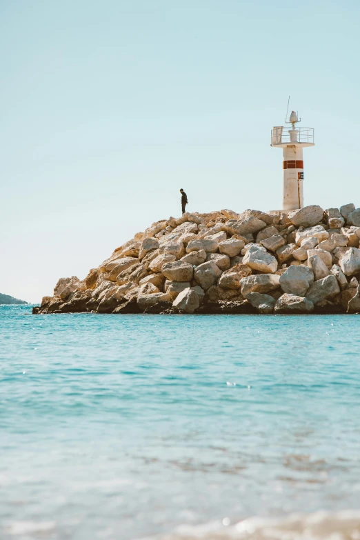 a light house standing on a rocky island over looking the ocean