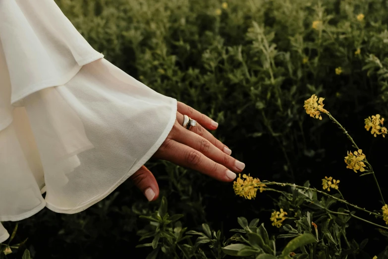 a person wearing white dress standing in a field with yellow flowers