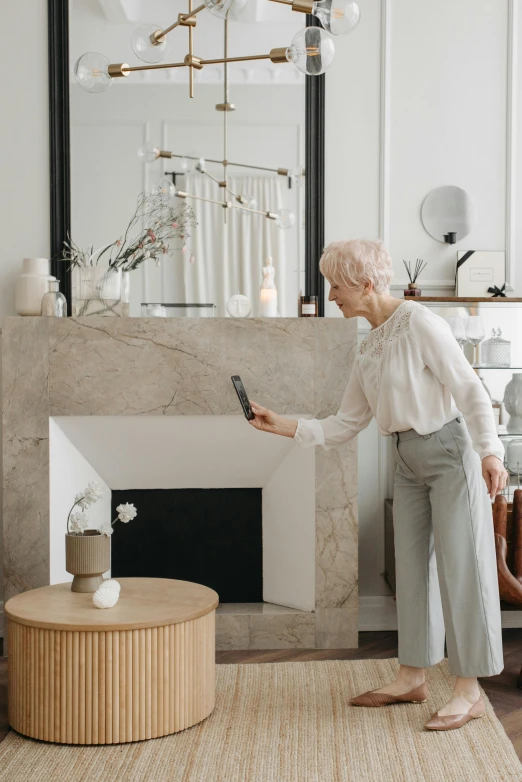 a woman is looking at her phone near a fireplace