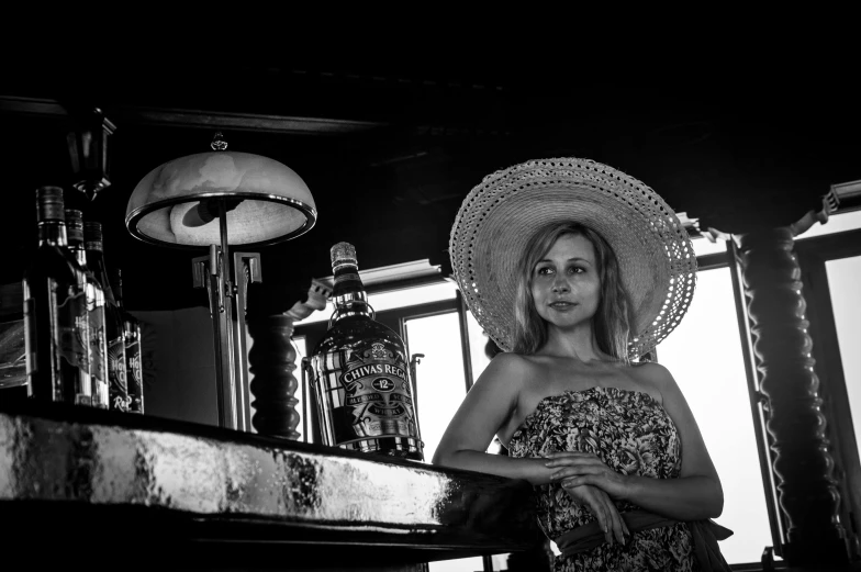 a woman with a large straw hat standing near a table with lamps