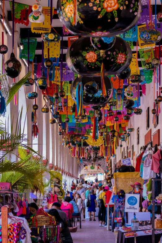 many kites hanging in the air at an outdoor market