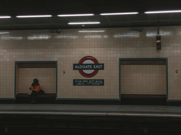 two people are sitting on a bench next to a train station