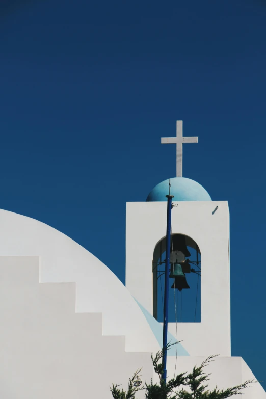 a white church with a cross and bell tower