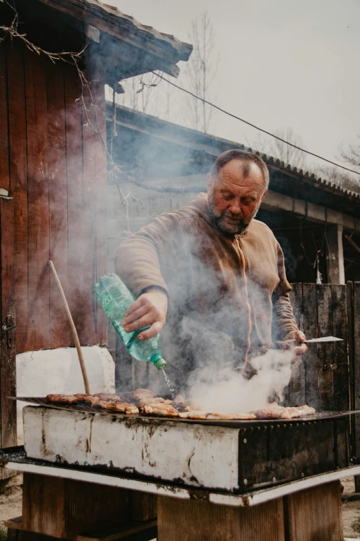 a man preparing food on the grill in the outdoors