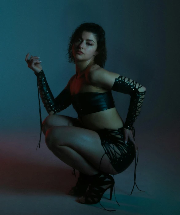 a woman kneeling down while posing in leather