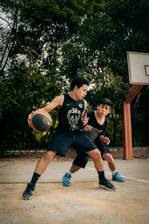 two young men play basketball together in a court