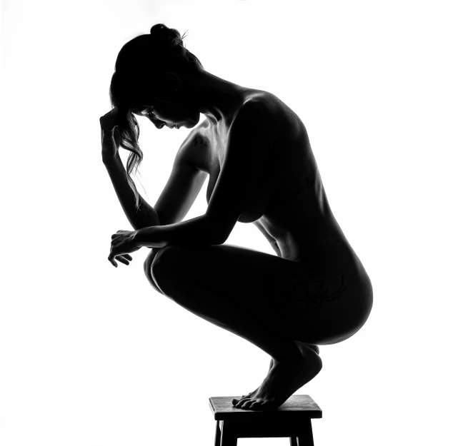 a woman is sitting on a stool with her hands in her hair