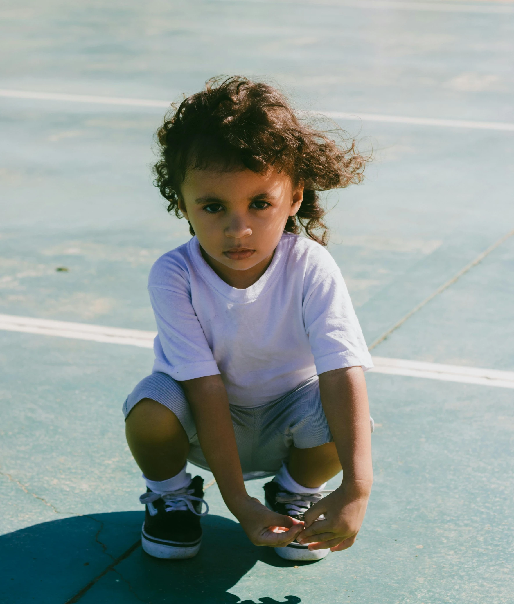 a small child crouched down on a tennis court