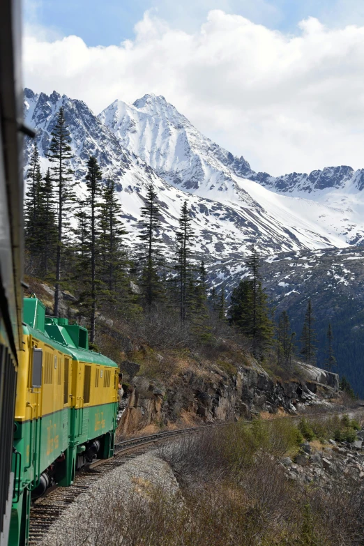 a train traveling down tracks next to a snow covered mountain