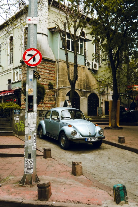 an old car is parked by a no parking sign