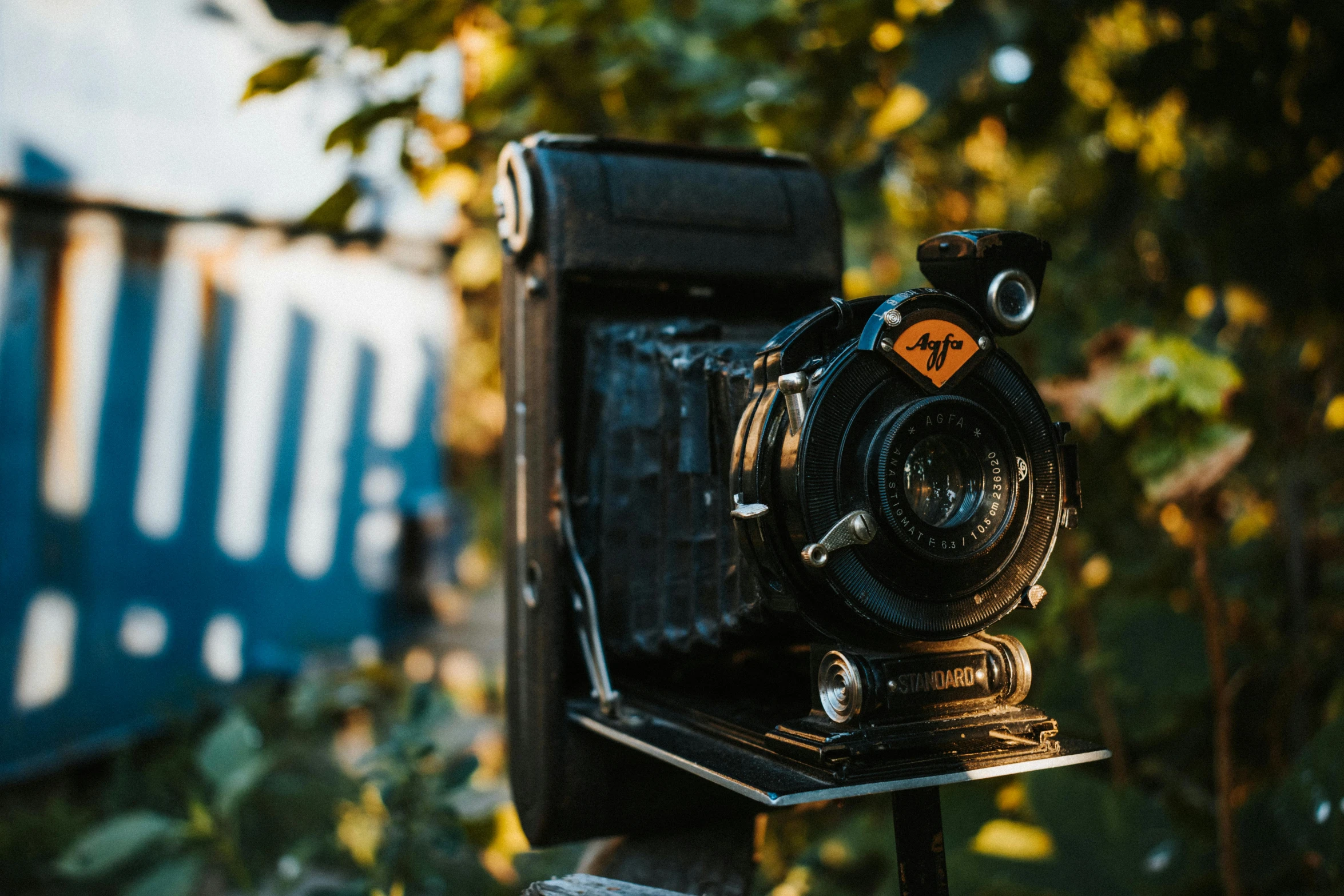 a vintage camera sits atop a wooden fence