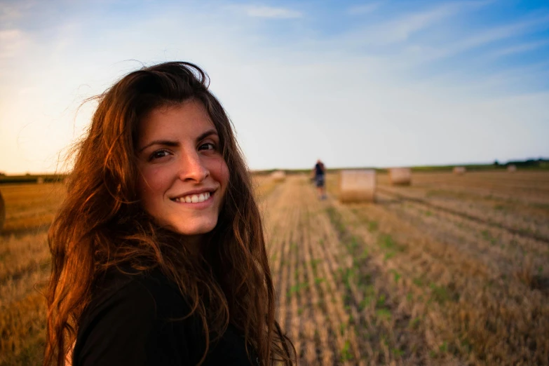 woman standing in a field in front of several bales