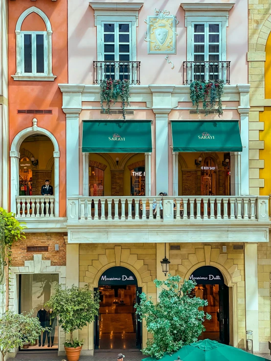 people sit on steps outside a colorful building under an umbrella