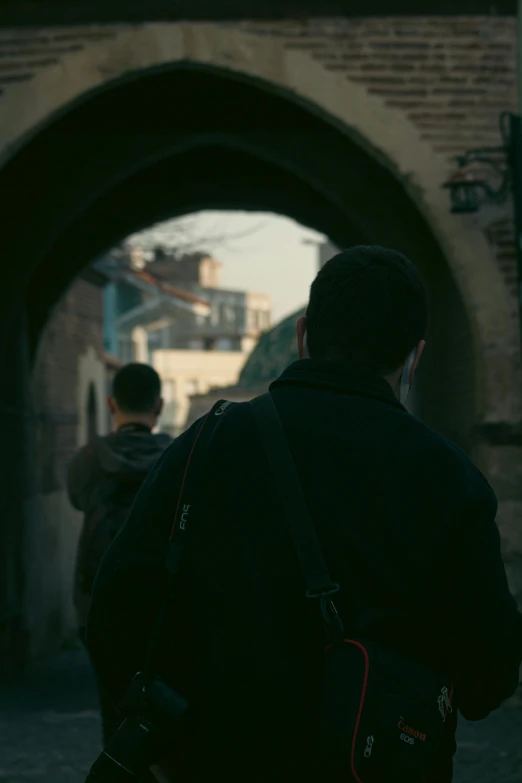 a man walking in front of an old tunnel