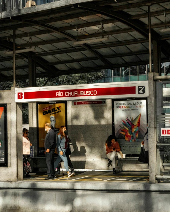 several people are standing outside of a bus stop