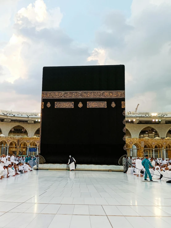 a crowd of people sitting around a large black wall