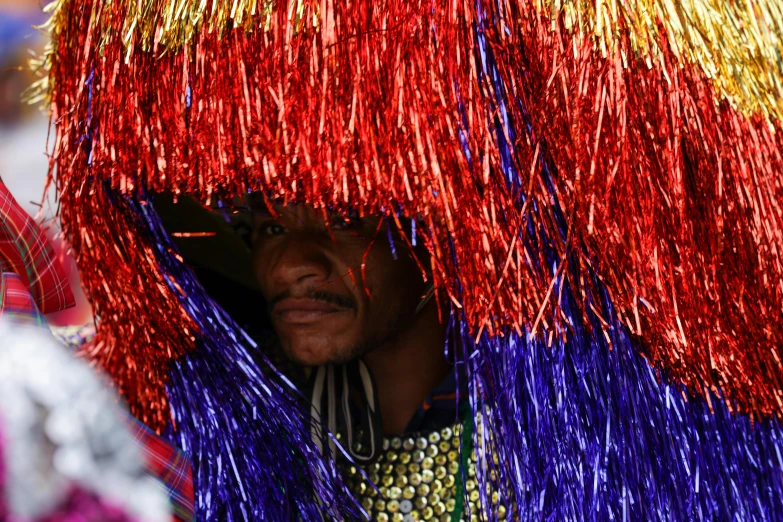 a man in colorful clothing stands beneath a straw umbrella