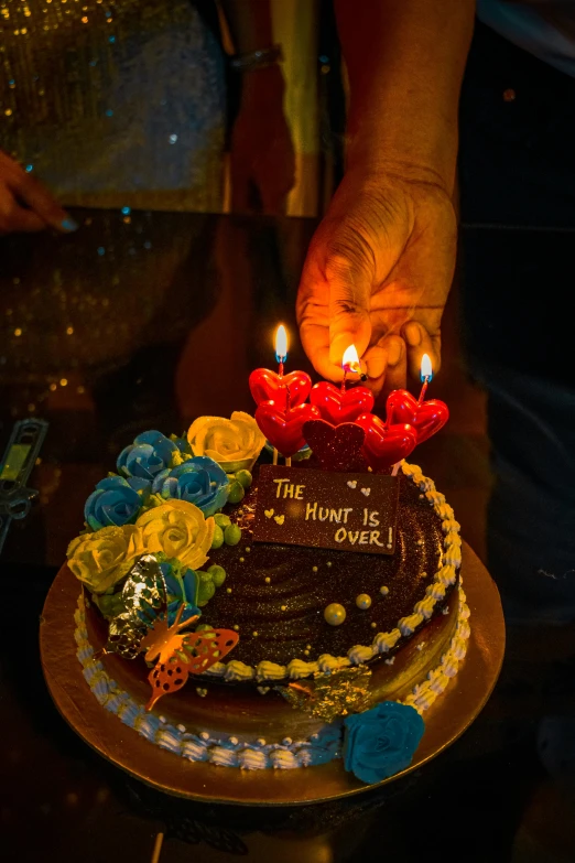 someone is holding a large cake with four candles in it
