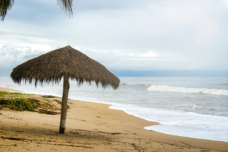 a hut sitting on top of a sandy beach next to the ocean