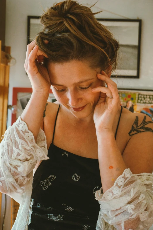 a beautiful woman touching her hair while wearing a top