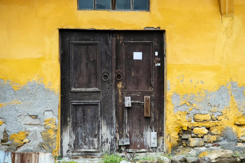 two brown doors sitting next to a yellow wall