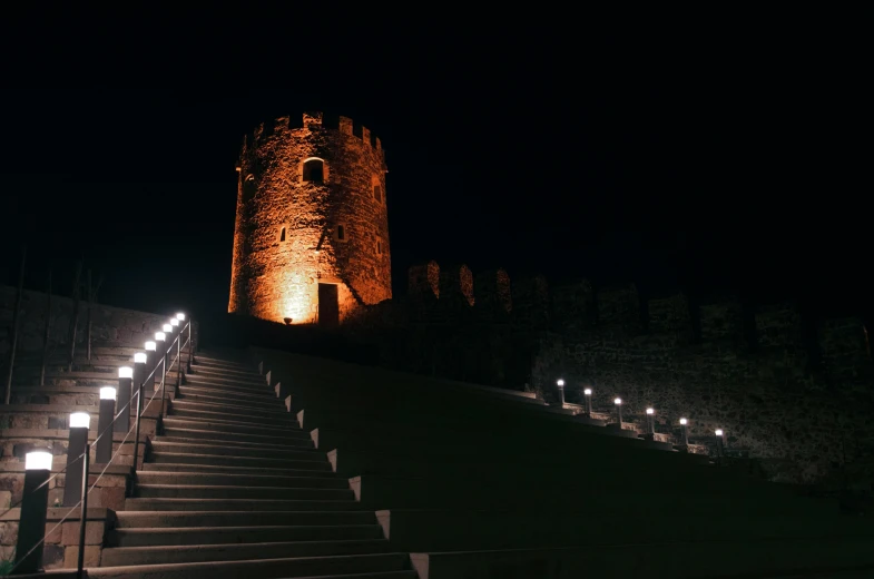 a stone building with lights on and stairs lit up