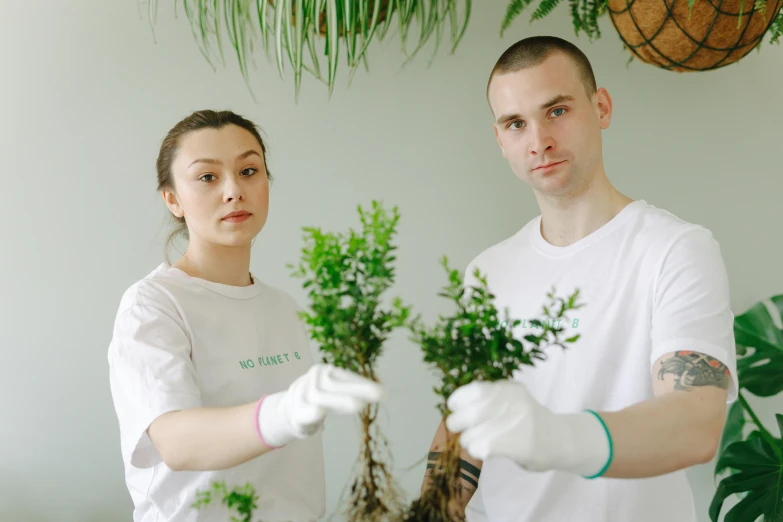 a man and woman are holding plants with white gloves