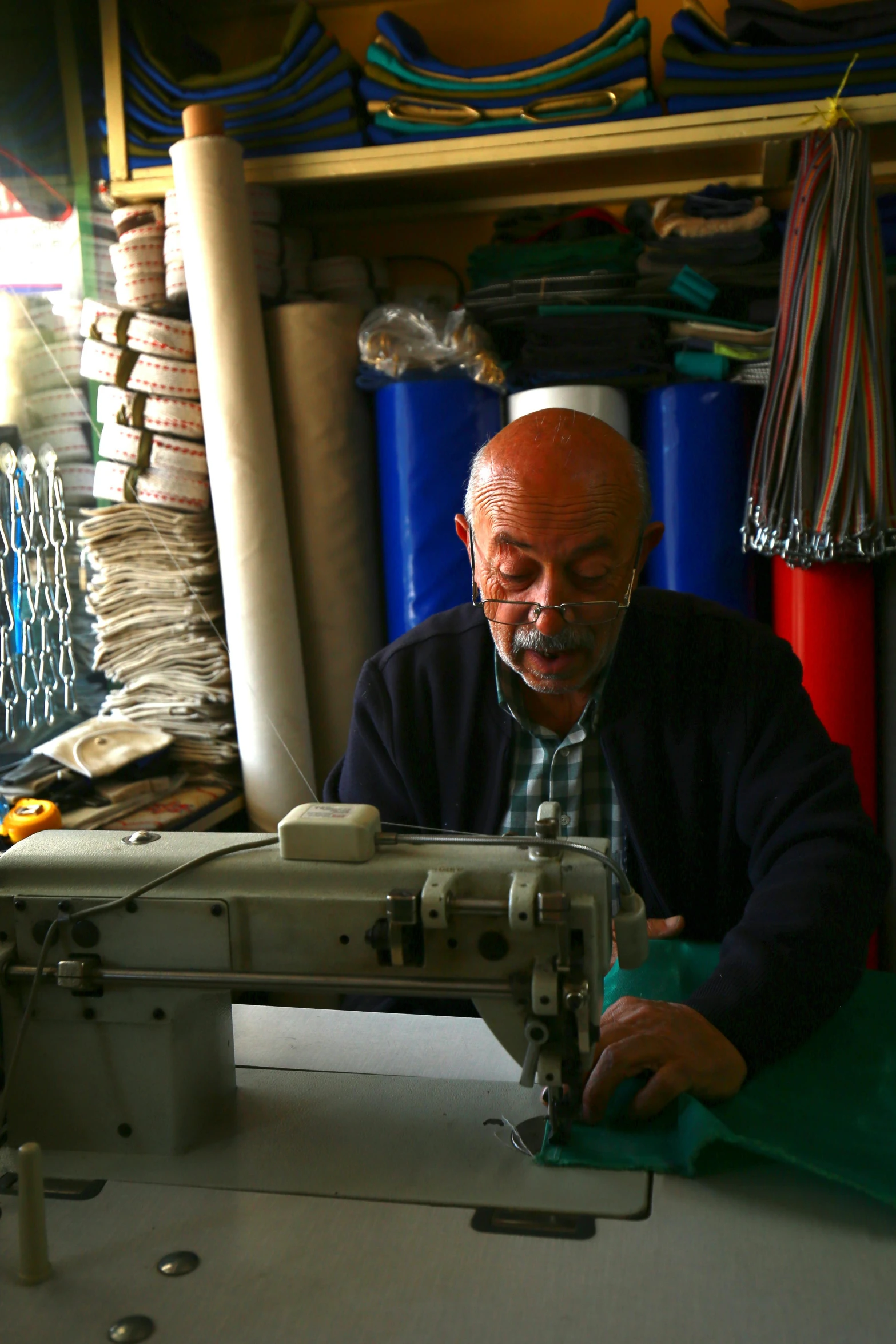 man working with sewing machine in a storage area