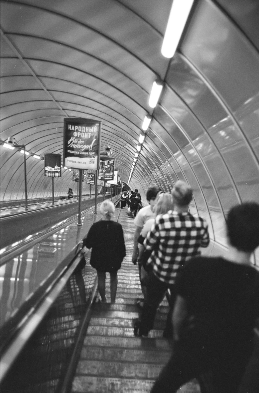 some people walk up the escalator in an underground tunnel