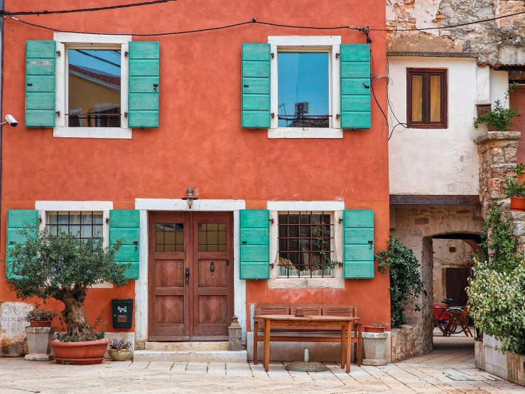 a colorfully painted building with green shutters and two benches