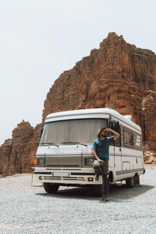 a man sitting next to a parked camper