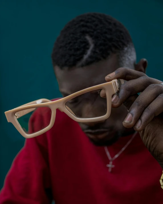 man looking at glasses against a green wall