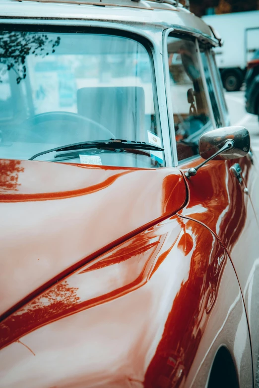 the back end of an older classic car, parked on a busy city street