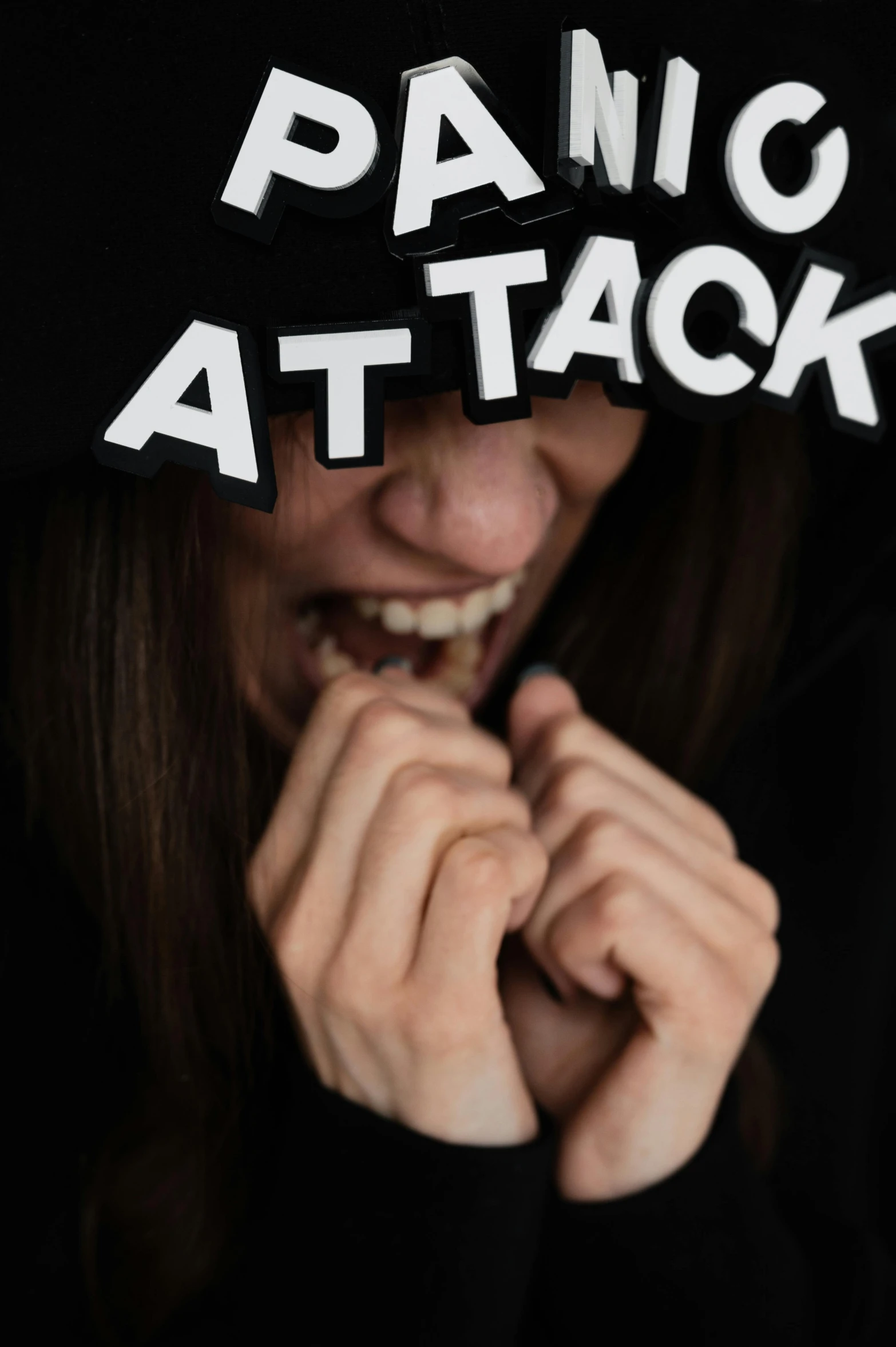 a woman wearing a fake baseball cap has her face covered by fake letters