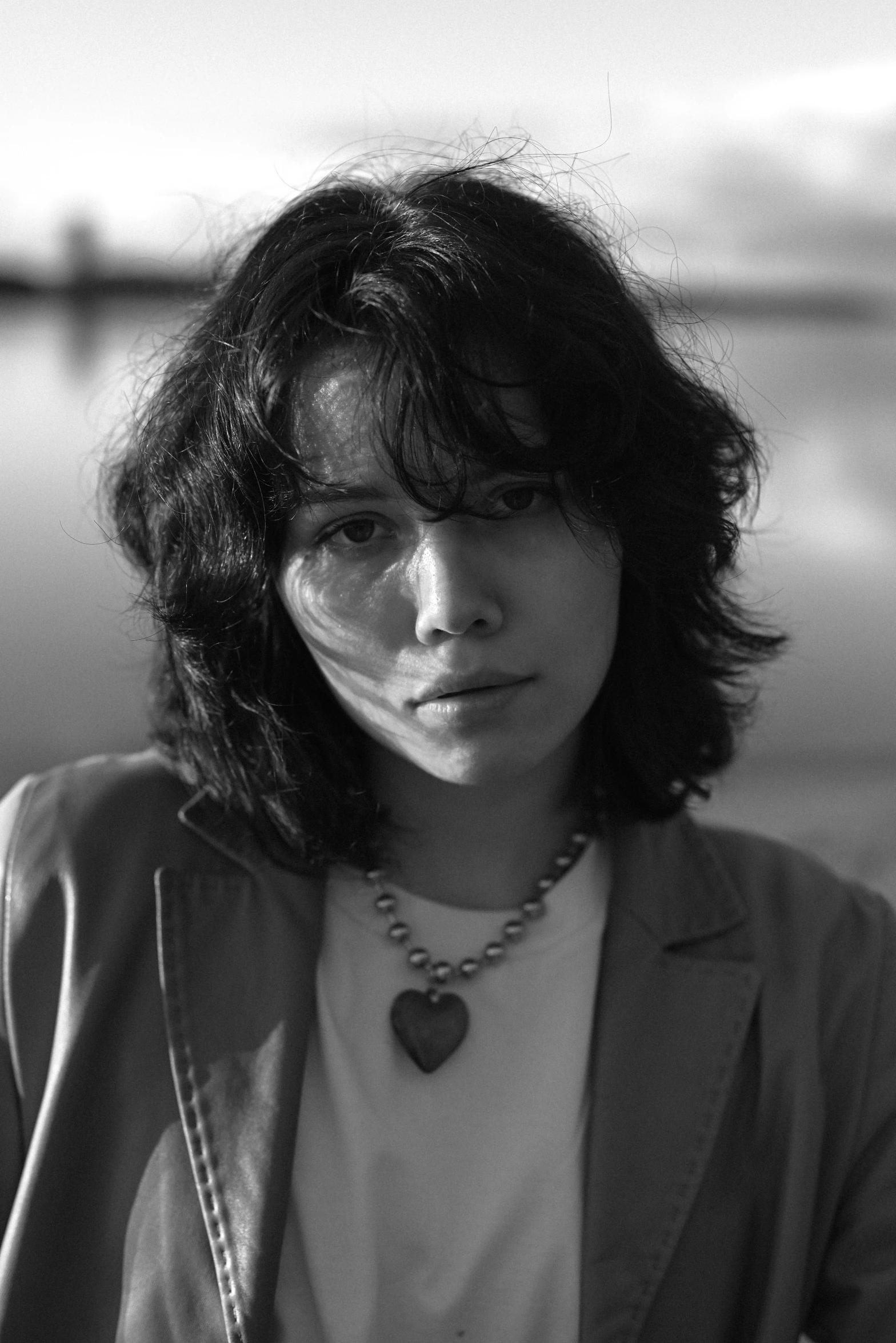 a woman is sitting and wearing a long necklace