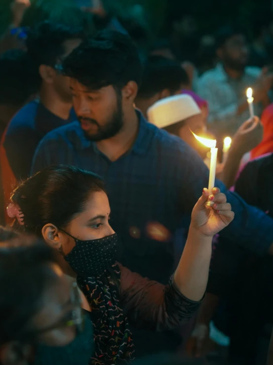 a woman holding a small candle with one arm raised