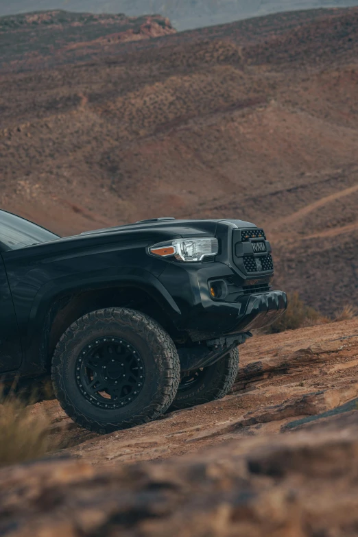 a black pickup truck is driving down a hill side