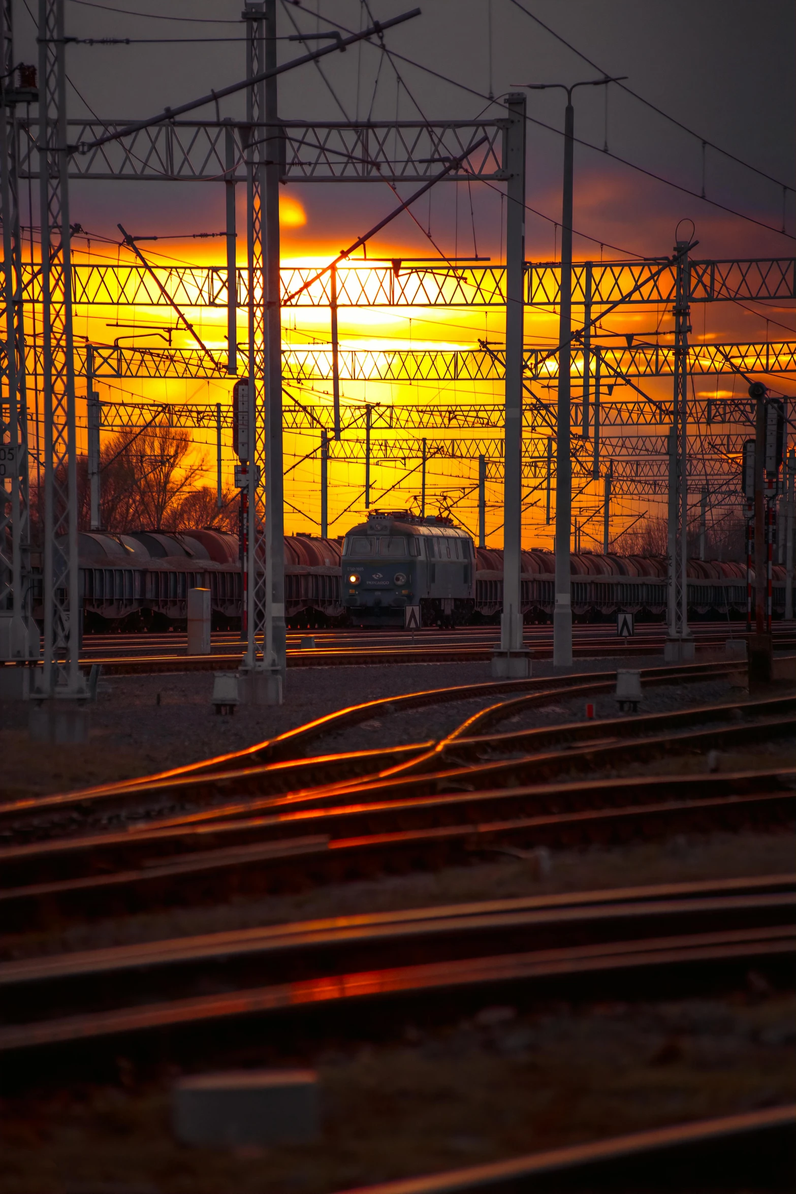 the sun shining in the distance behind a large set of power lines