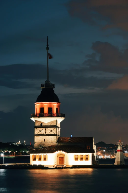 a large white building with an illuminated clock on top and a flag pole