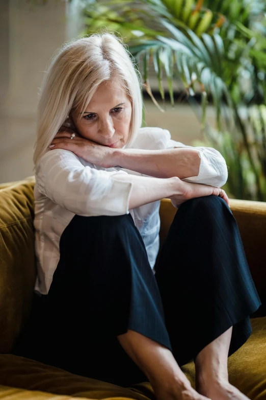 a woman sitting on a couch with her hands behind her head