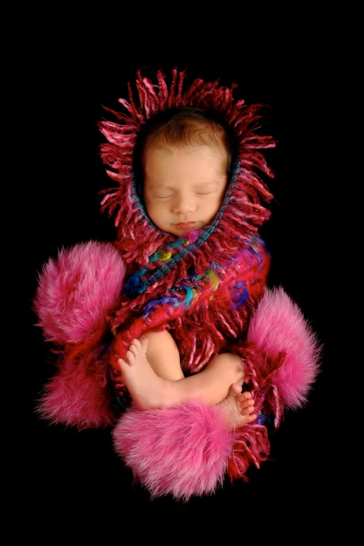 baby wrapped in pink knit with pink fluffy trim