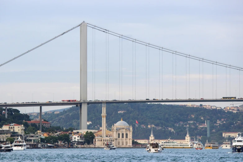 a view of boats sailing on the water in front of a bridge