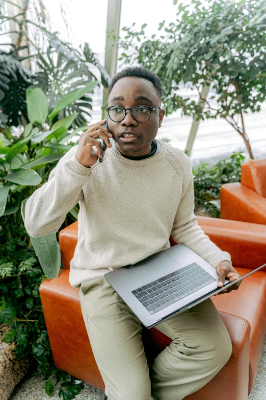 a woman in glasses sits on a red chair while talking on her phone