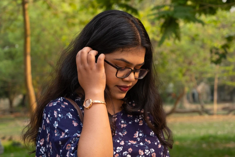 a woman is standing in the park wearing glasses