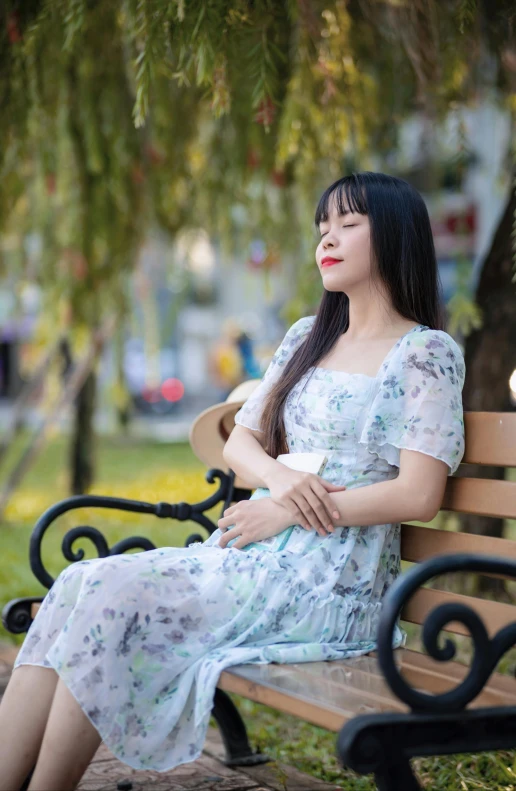 a young woman sitting on a bench beneath a tree