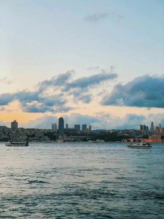 the city skyline is shown over water with boats floating on it