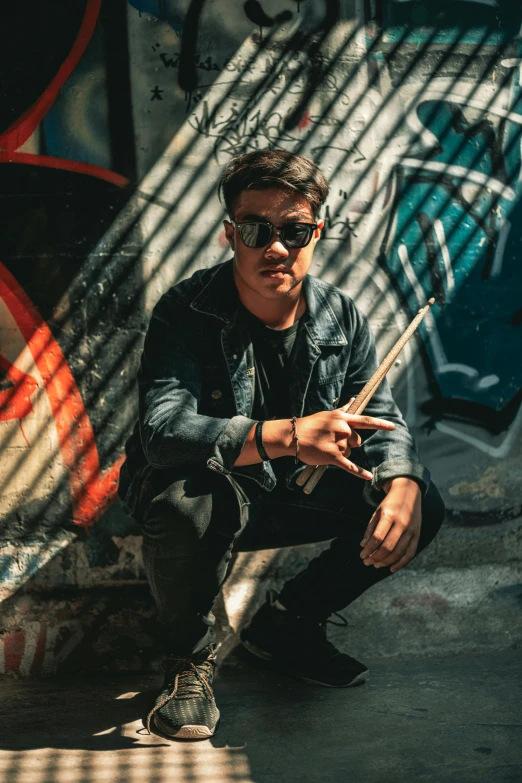 a man crouching on the ground in front of a wall with graffiti