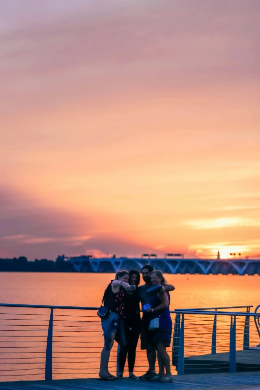 three women are standing on a deck and one is hugging her neck