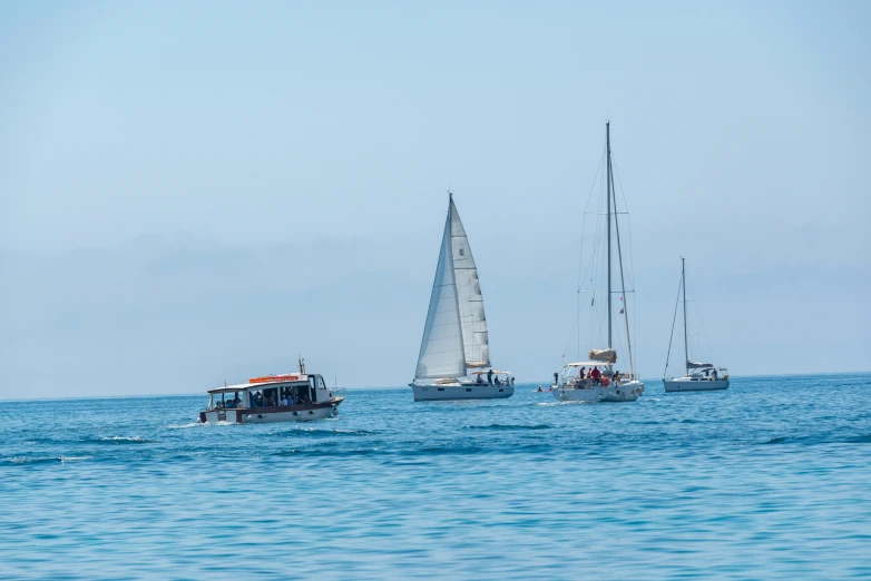 three sailboats with sails in the water