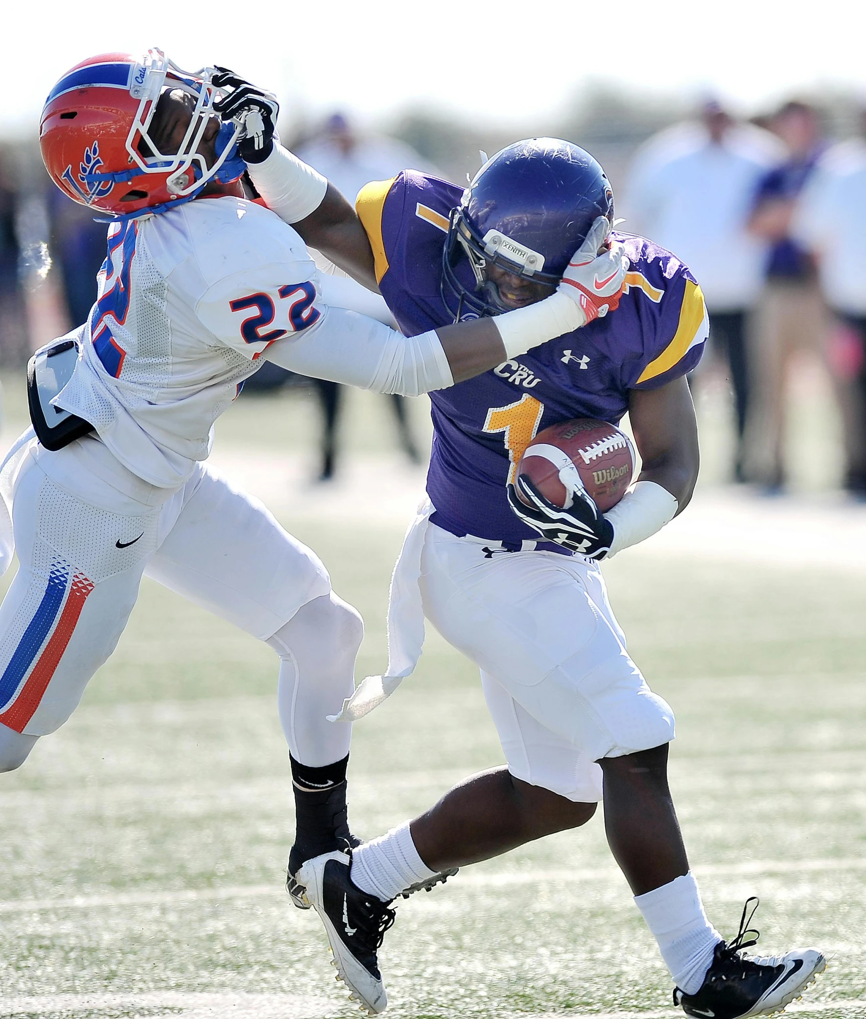 two football players run after the ball during a game